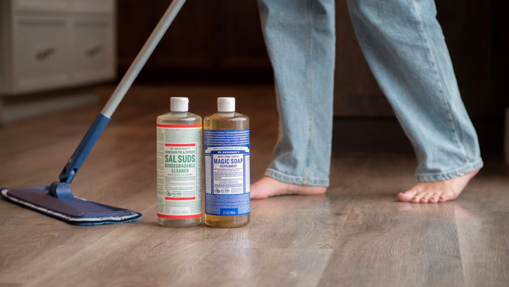 Dr. Bronner's Sal Suds and Castile soap on floor while someone mops behind.