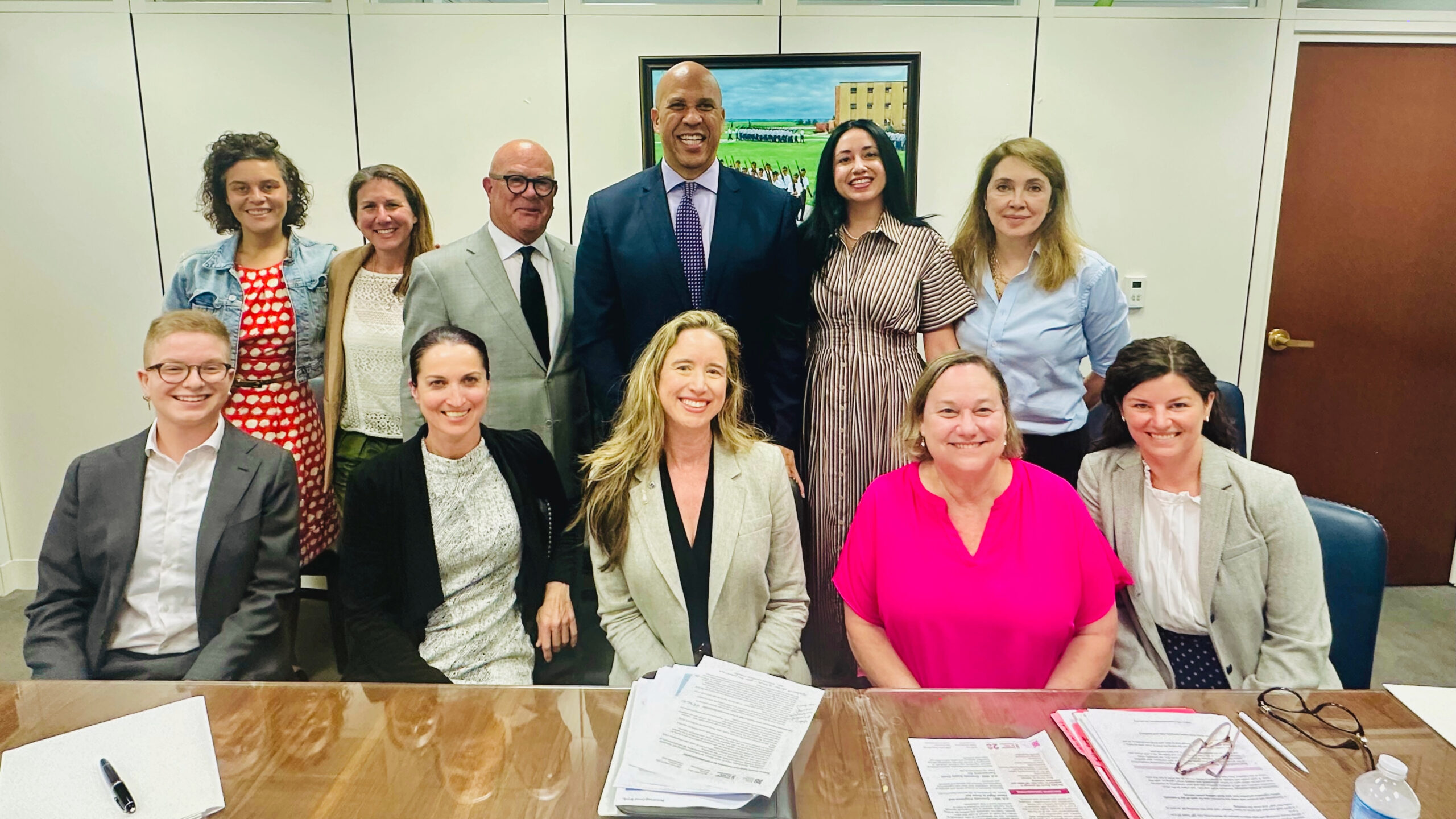 A group of smiling people including Senator Cory Booker, his team, Lisa Bronner and other business professionals. 