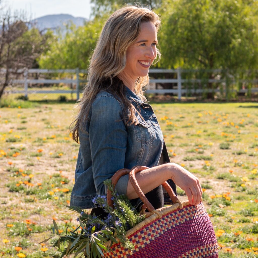 Lisa smiling, walking with a basket full of plants.